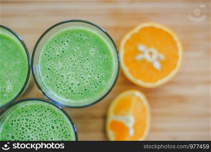 Arrangement of a fresh green healthy smoothies and fruits on a wooden background.