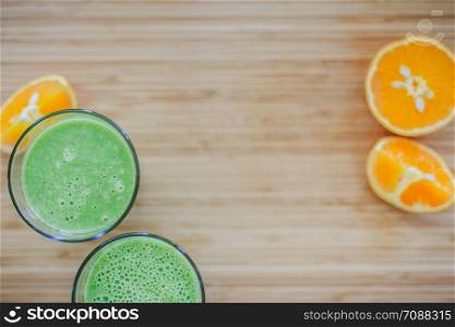 Arrangement of a fresh green healthy smoothies and fruits on a wooden background. Text space.