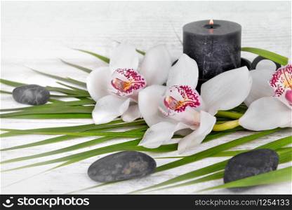 arrangement with white orchids, pebbles and candle on white table . arrangement on white table with orchid, pebbles and candle