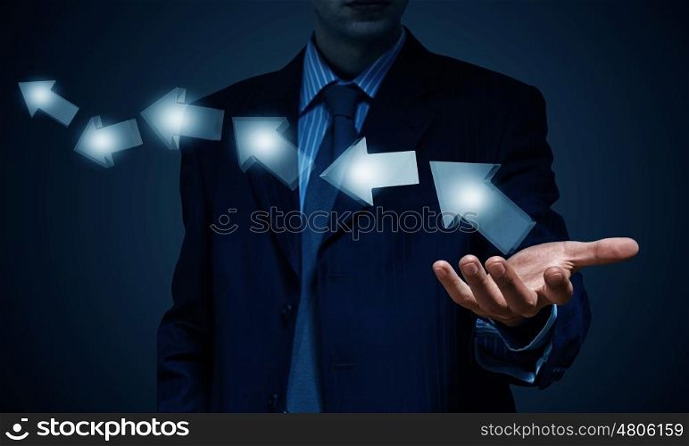 Arrow icons as growth concept. Businessman holding arrows in palm over dark background