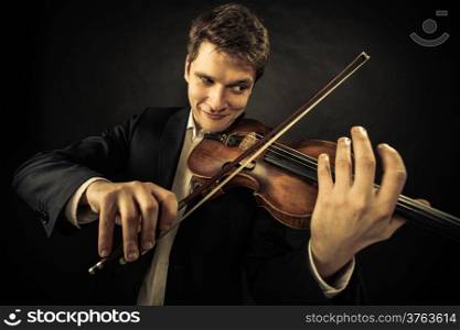 Art and artist. Young elegant emotional man violinist fiddler playing violin on dark gray. Classical music. Studio shot.