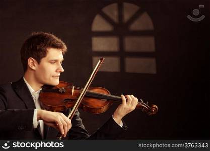 Art and artist. Young elegant in love man violinist fiddler playing violin under the window at night. Classical music. Studio shot.