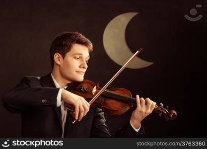 Art and artist. Young elegant in love man violinist fiddler playing violin at moon night. Classical music. Studio shot.