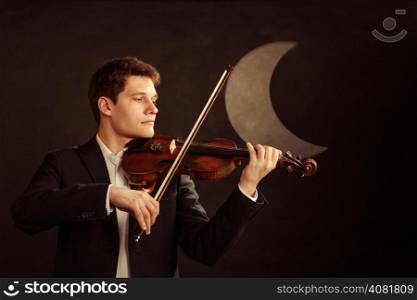 Art and artist. Young elegant in love man violinist fiddler playing violin at moon night. Classical music. Studio shot.