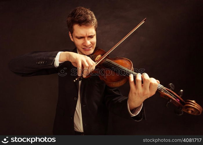 Art and artist. Young elegant man emotional violinist fiddler playing violin on black. Classical music. Studio shot.