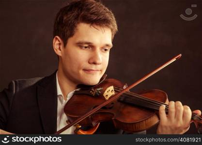 Art and artist. Young elegant man violinist fiddler playing violin on black. Classical music. Studio shot.
