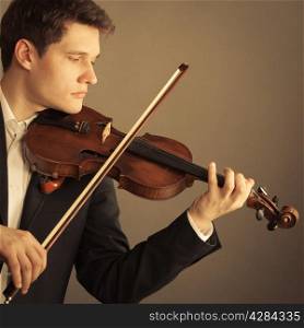 Art and artist. Young elegant man violinist fiddler playing violin on brown. Classical music.