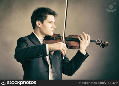 Art and artist. Young elegant man violinist fiddler playing violin on brown. Classical music.