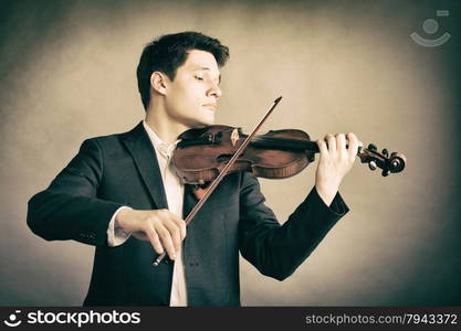 Art and artist. Young elegant man violinist fiddler playing violin on brown. Classical music.