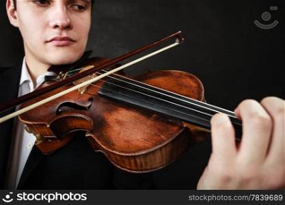 Art and artist. Young elegant man violinist fiddler playing violin on dark gray. Classical music. Studio shot.