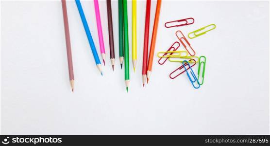 Art and drawing concepts, Colored crayon pencils and clips at top corner on white background with copy space. Wide web banner, poster, brochure template design. Top view, Closeup.