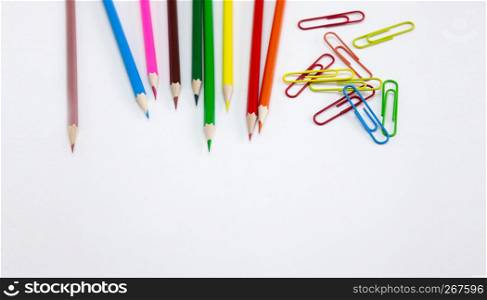 Art and drawing concepts, Colored crayon pencils and clips at top corner on white background with copy space. Wide web banner, poster, brochure template design. Top view, Closeup.