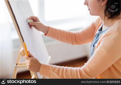 art, creativity and people concept - artist with eraser and still life picture of flower in vase on easel at studio. artist with eraser drawing picture at art studio