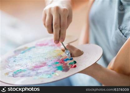 art, creativity and people concept - close up of artist with palette knife painting still life on easel at studio. artist with palette knife painting at art studio