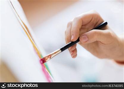 art, creativity and people concept - hand of artist with brush painting picture. hand of artist with brush painting picture