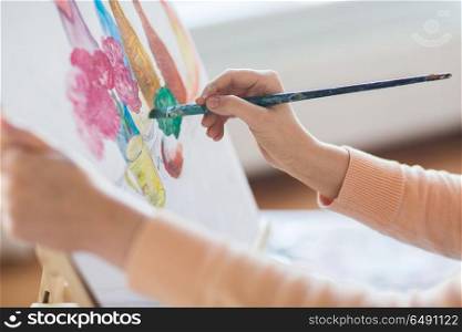 art, creativity and people concept - hands of artist with paint brush and easel painting still life on paper at studio. artist with brush painting still life at studio. artist with brush painting still life at studio