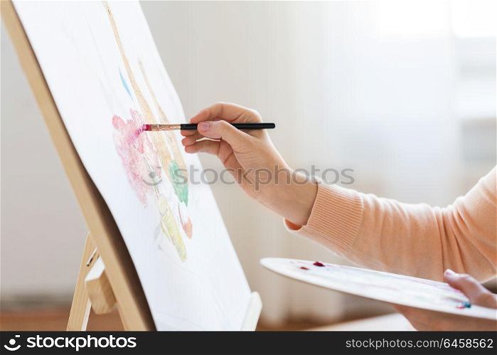 art, creativity and people concept - hands of artist with palette and brush painting still life on paper at studio. artist with palette and brush painting at studio