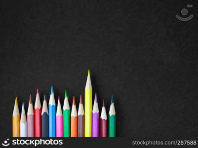 Art drawing concept, Colorful crayon pencils in a row with selective focus on yellow color on black canvas with texture background with copy space. Design for banner, poster, brochure, advertising.