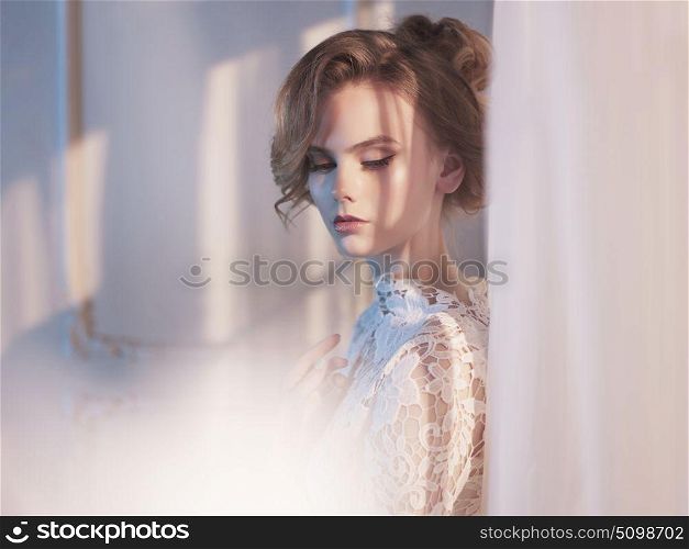 Art fashion photo of beautiful gorgeous woman in lace dress at the window. Beauty and health. Wedding style. Bridal morning