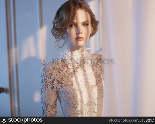 Art fashion portrait of beautiful gorgeous woman in lace dress at the window. Beauty and health. Wedding style. Bridal morning
