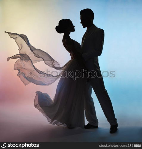 Art fashion studio photo of wedding couple silhouette groom and bride on colors background. Art Wedding style. Flowing dress. Dance of groom and bride