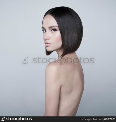 Art fashion studio portrait of beautiful brunette with short haircut. Young sexy model pose in white studio with naked body. Nude lady with classic professional make-up