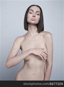 Art fashion studio portrait of beautiful brunette with short haircut. Young sexy model pose in white studio with naked body. Nude lady with classic professional make-up
