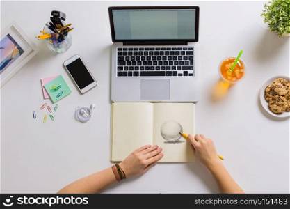 art, people and freelance concept - woman hands with pencil drawing ball in notebook at home office. woman hands drawing in notebook at home office