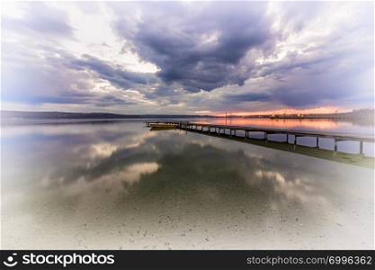 Art photo of a wooden pier at the lake. Water reflection