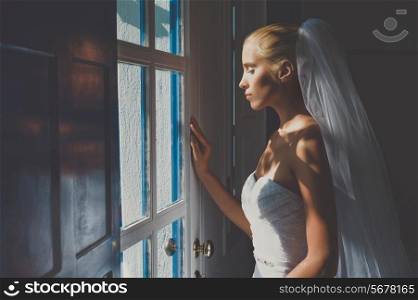Art photo of beautiful bride waiting at the window