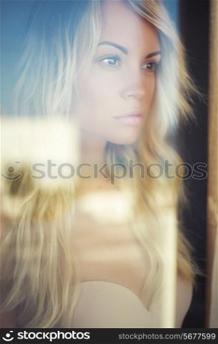 Art portrait of beautiful blonde through the glass