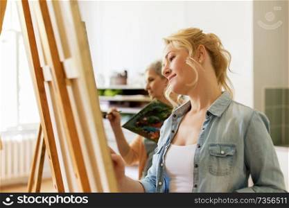 art school, creativity and people concept - woman with easel drawing at studio. woman with easel drawing at art school studio