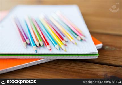 art, school, education, drawing and object concept - close up of crayons or color pencils on notebook paper