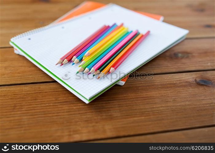 art, school, education, drawing and object concept - close up of crayons or color pencils on notebook paper