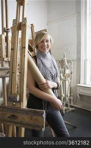 Art student with rolled-up artwork in studio, portrait