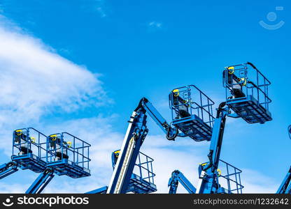 Articulated boom lift. Aerial platform lift. Telescopic boom lift against blue sky. Mobile construction crane for rent and sale. Maintenance and repair hydraulic boom lift service. Crane dealership.