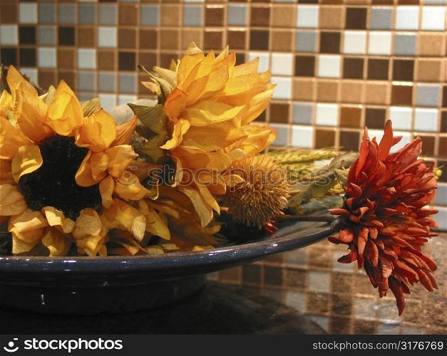 Artificial flowers in a bowl as kitchen interior decoration