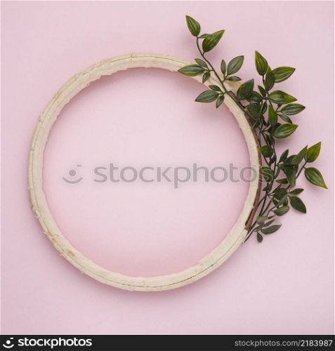 artificial green twig near wooden border frame pink background