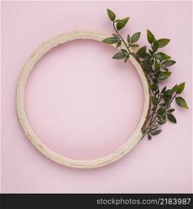artificial green twig near wooden border frame pink background