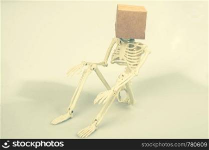 artificial human skeleton sitting with a box on his skull