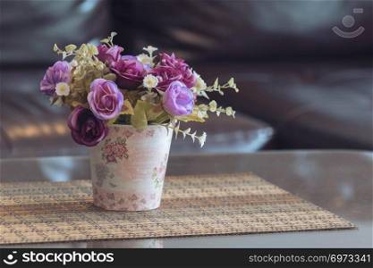 Artificial plants and roses in pot with blurred background