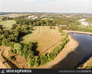 Artificial pond in the Harz Mountains with a neighbouring meadow and a small town in the background, aerial photo with the drone.
