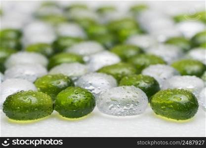 artificial round stones with water drop of green and white color. imitation pebbles. round plastic pebbles