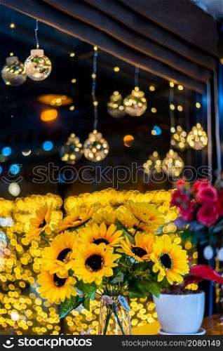 artificial sunflower in glass vase for decoration for Christmas decoration lights in the shape of on Bokeh background Decoration During Christmas and New Year.