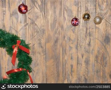 artificial wreath with ribbon, and shiny, colorful balls on wooden background. christmas decorations. christmas decorations on wooden background