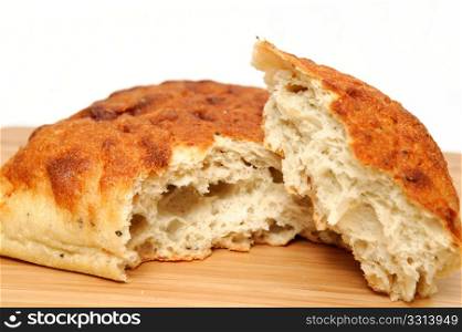 Artisan Bread. A square loaf of artisan bread with a corner of the loaf torn off on a wooden cutting board