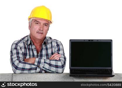 Artisan resting on concrete wall with computer
