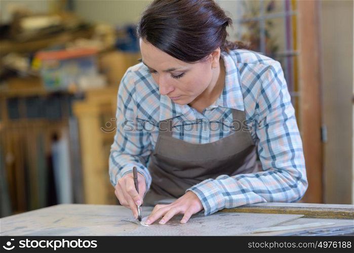 artisan worker drawing round stencil in workshop