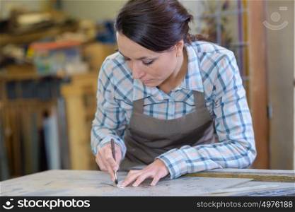 artisan worker drawing round stencil in workshop