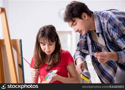 Artist coaching student in painting class in studio